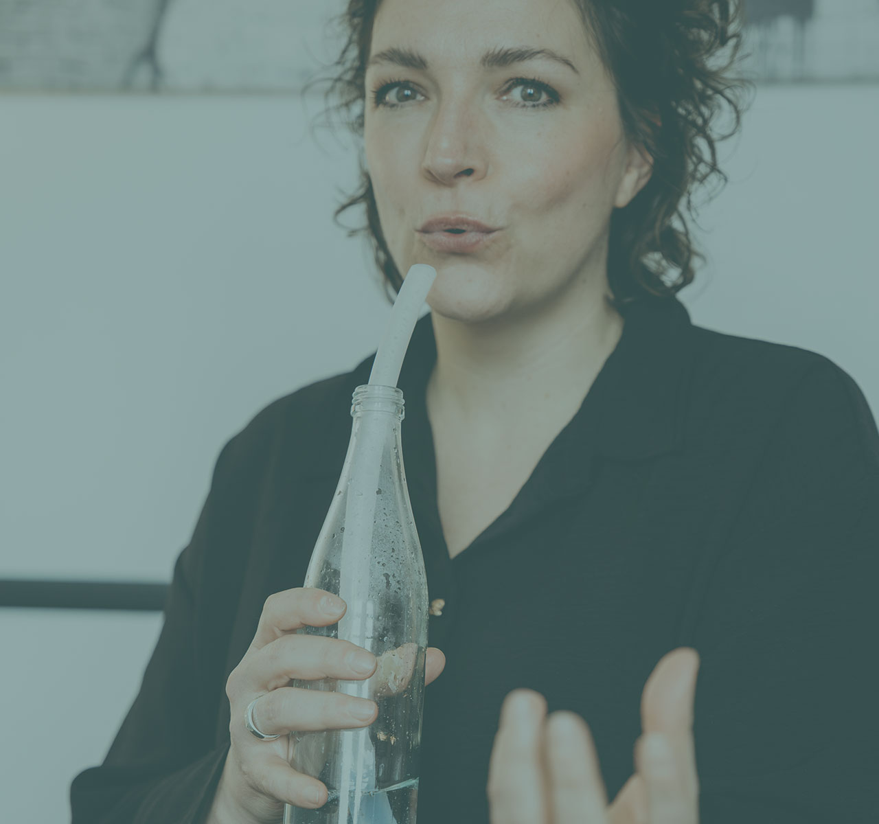 Eine Logopädin demonstriert eine Atem- und Stimmübung mit einer Wasserflasche und Trinkhalm